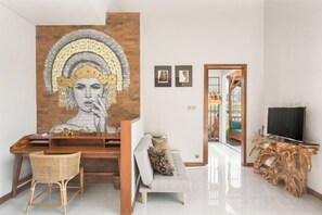 A living room with a sofa, a coffee table, a TV, and a wall with a large artwork. - Dijero at Umah Bali (Bali)