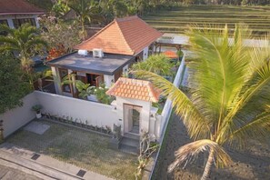 A house with a tiled roof, a small attached structure, and a palm tree. - Dijero at Umah Bali (Bali)
