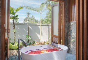 A spa area with a large bathtub filled with rose petals and bath products. - Dijero at Umah Bali (Bali)