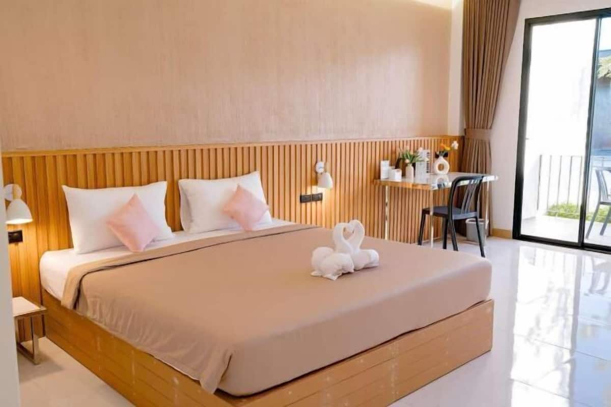 Ein Hotelzimmer mit Bett, Nachttisch, Lampe und Blick ins Freie.