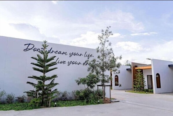 A modern building with a motivational quote on the wall, surrounded by greenery. - Bed Resort Sadao (Sadao)