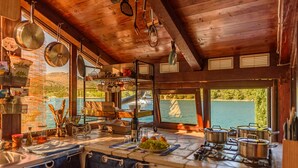 A rustic kitchen with wooden beams, a view of a lake, and various cooking utensils and pots. - ZadarVillas Off-Grid Private Island Retreat (Sali)