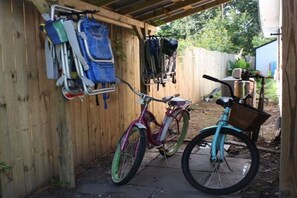 A bicycle parked in a wooden fenced area with a metal rack holding various items.