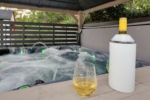 A hot tub with water jets, a glass of white wine, and a white bottle.