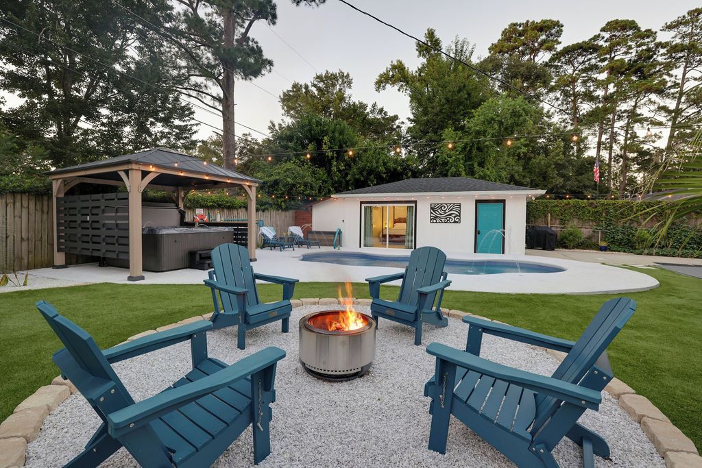 A backyard with a fire pit, outdoor seating, and a small building with a door.