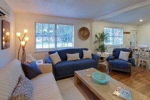 A living room with a blue sofa, a wooden coffee table, and a dining area with chairs and a table.
