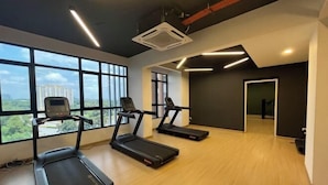 A gym with treadmills, a rowing machine, and large windows offering a city view. - Putrajaya Antara Residence Air-Con Suite Facing Lake View (Putrajaya)