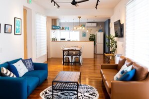 A modern living room with a blue sofa, a brown leather sofa, and a dining area with a table and chairs. - HOTEL YANBARUNIA (Nago)
