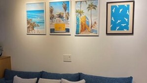 Uma sala de estar com um sofá azul e três quadros na parede.