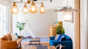 Uma sala de estar com sofá, mesa de centro, mesa de jantar e uma tenda.