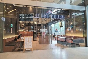 A restaurant with a glass facade, outdoor seating, and a menu board outside. - Luxury Family Summer Suite KLCC 5 min walk 1BR by Amna (Kuala Lumpur)