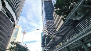 A modern high-rise building with a prominent tower in the background. - Luxury Family Summer Suite KLCC 5 min walk 1BR by Amna (Kuala Lumpur)