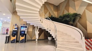 A modern interior with a spiral staircase, a reception area, and a large potted plant. - Luxury Family Summer Suite KLCC 5 min walk 1BR by Amna (Kuala Lumpur)