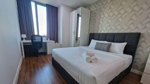 A hotel room with a bed, a desk, a chair, and a wardrobe. - Luxury Family Summer Suite KLCC 5 min walk 1BR by Amna (Kuala Lumpur)