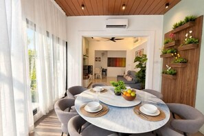 Un espace repas moderne avec une table ronde, des chaises grises et un plafond en bois.
