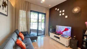 A modern living room with a sofa, TV, and a sliding glass door leading to an outdoor area. - Fairy Retreat Private Pool@12-13pax (Ipoh)