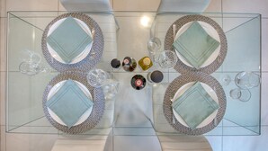 Une table à manger dressée pour quatre personnes, avec des assiettes et des serviettes à motifs, des verres et des condiments.