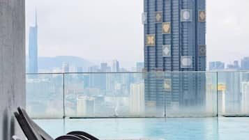 A poolside area with a view of a city skyline, including a tall building with a unique facade.
