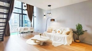 A modern living room with a sofa, coffee table, and dining area. - EkoCheras LumaStay (Kuala Lumpur)