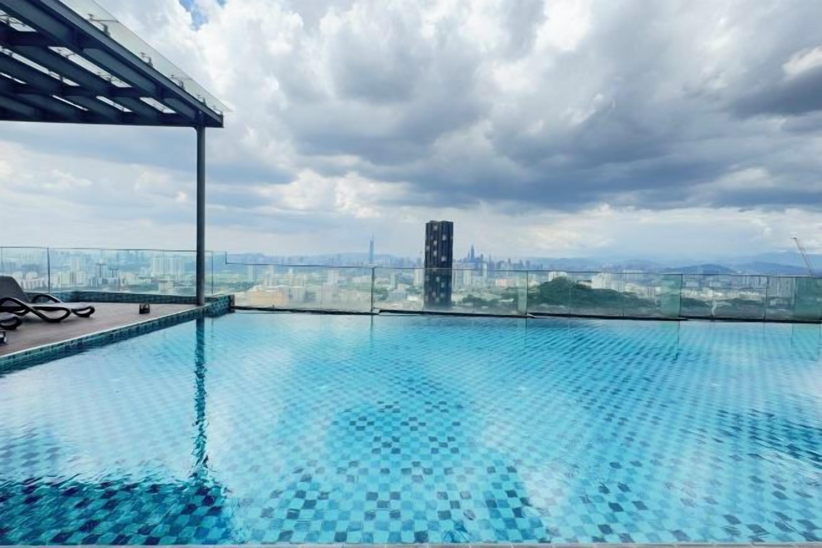 Una piscina infinita en la azotea con vistas a la ciudad, un área de estar cubierta y una barandilla de vidrio.