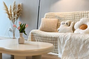 A cozy room with a round table, a cushioned sofa with decorative pillows, and a vase with flowers. - EkoCheras LumaStay (Kuala Lumpur)