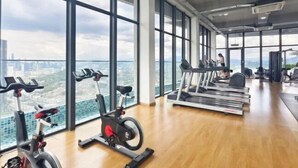 A gym with cardio equipment and large windows offering a city view. - EkoCheras LumaStay (Kuala Lumpur)
