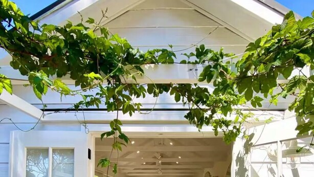 Un intérieur lumineux, avec un plancher en bois, un coin repas avec des chaises et une cuisine à l’arrière-plan.