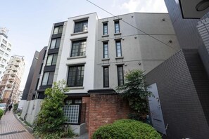 A multi-story residential building with a modern architectural design, featuring a combination of white and grey facades, large windows, and a brick base. - Leclerc Higashi-Shinjuku (Shinjuku)