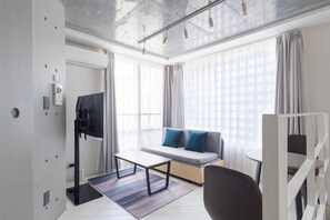 A modern hotel room with a sofa, a flat-screen TV, a coffee table, and a staircase. - Leclerc Higashi-Shinjuku (Shinjuku)