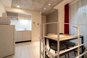 Cozinha compacta com eletrodomésticos modernos, área de refeições com mesa e cadeiras, e vista pela janela.