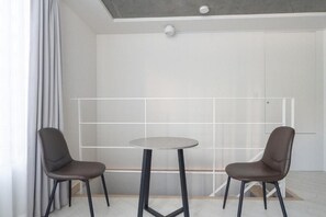 Ett modernt rum med två stolar och ett bord, ett vitt tak och en lampa.