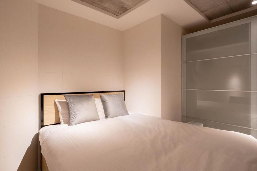 A modern bedroom with a large bed, a nightstand, and a wall-mounted cabinet.