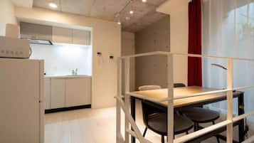 A modern kitchen with white cabinets, a built-in oven, and a dining area with a table and chairs.