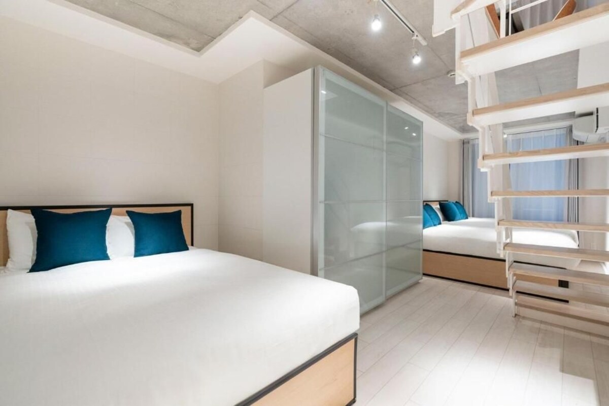 A modern bedroom with a large bed, a glass wardrobe, and a built-in bench.