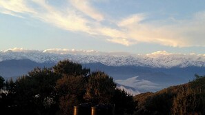 A mountainous landscape with snow-capped peaks and a forested foreground. - Hotel Himalayan Glacier (Baluwapati Deupur)