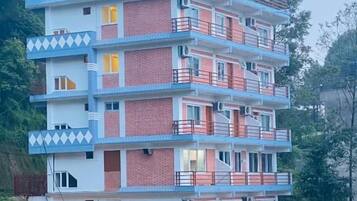 Un edificio de varios pisos con techo plano, balcones y unidades de aire acondicionado.