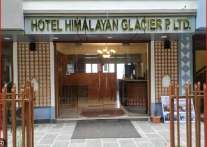 Hotelli Himalayan Glacier P. Ltd:n sisäänkäynti, jossa on vastaanottotiski ja kyltti oven yläpuolella.