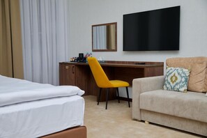 A hotel room with a bed, a desk with a chair, a television, and a sofa. - Grand Plaza Hotel Samarkand (Samarkand)