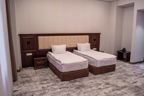 A double room with two single beds, a wooden headboard, a small bedside table, and a carpeted floor. - Grand Plaza Hotel Samarkand (Samarkand)