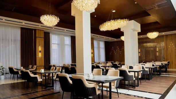 A spacious hotel dining area with multiple tables and chairs, large chandeliers, and a modern interior design. - Grand Plaza Hotel Samarkand (Samarkand)