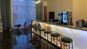 A bar area with a marble countertop, green bar stools, and a minibar. - Grand Plaza Hotel Samarkand (Samarkand)