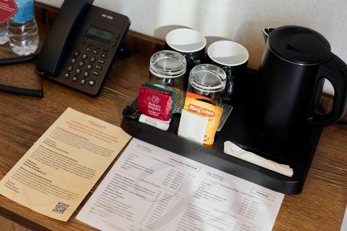 A hotel room's breakfast bar area with a coffee maker, sugar packets, a menu, and a phone.