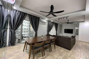 Un salon moderne comprenant une table à manger, un canapé, un ventilateur de plafond et un téléviseur.