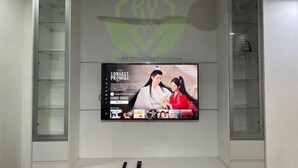 Een flatscreen-tv aan een muur bevestigd, met een logo erboven.