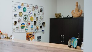 A room with a wall-mounted display of various decorative plates, a black cabinet, and a wooden counter.
