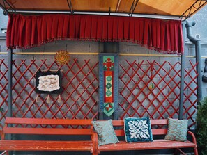 Una panca rossa con due cuscini, una tenda rossa e un muro decorato con motivi solari e geometrici.