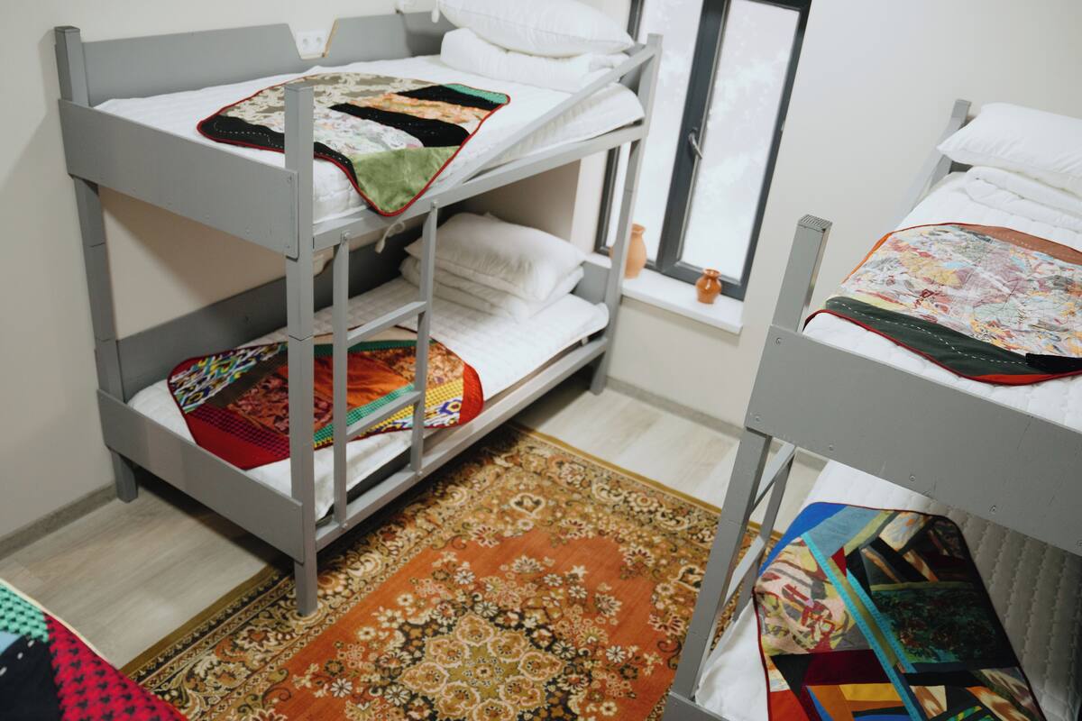 Quarto com beliche, tapete estampado e janela com vista.