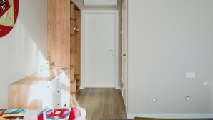 A bedroom with a wooden wardrobe, a bed with a colorful quilt, and a white door.