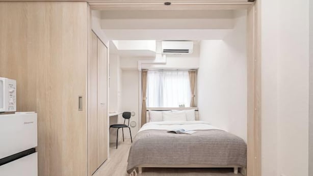 Ein kleines Hotelzimmer mit einem Bett, einem Schreibtisch und einer Klimaanlage.