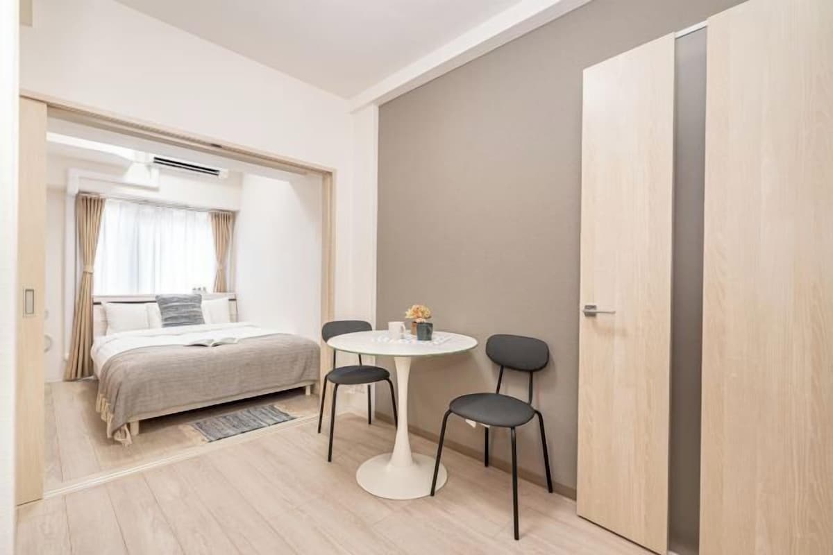 Ett modernt hotellrum med en säng, ett runt bord med stolar och en garderob.